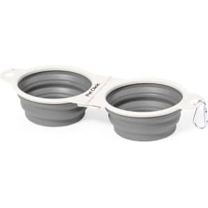 A foldable pet bowl with two grey compartments, featuring a connector and a clip for easy portability.