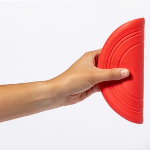 A red Frisbee held in a hand, featuring a curved design and smooth surface. It has a logo on it.