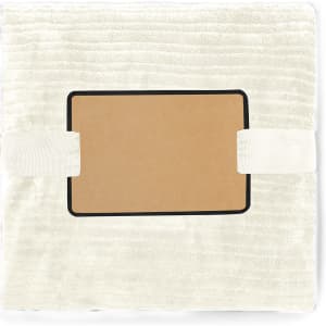 A cream-coloured blanket with a soft texture, featuring a branding logo and strap for secure storage.