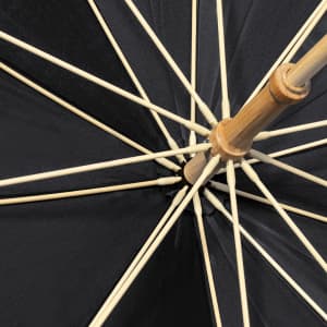 An umbrella featuring a black canopy and a wooden frame with ribbing, showcasing its interior structure.