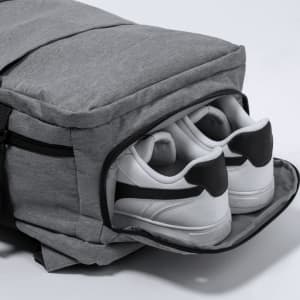 A grey Myriax backpack with a dedicated compartment holding white sneakers. It features branding on the exterior.