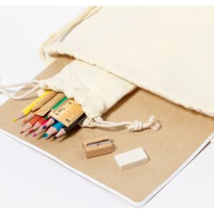 A cream drawstring pouch containing coloured pencils, a sharpener, and an eraser on a craft paper surface.