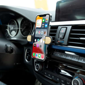 A phone holder in a car, featuring a sleek design with a wooden accent, securely holds a smartphone in place.