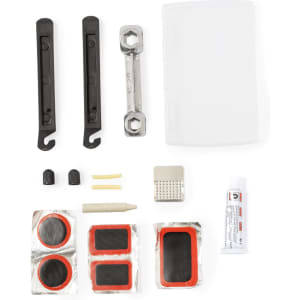 A bike repair kit featuring black tyre levers, a multi-tool, and various patches, along with a tube of adhesive.