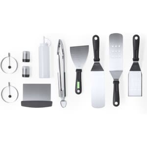 A barbecue set featuring stainless steel tongs, spatulas, and bottle, with black and silver accents. Includes additional components.
