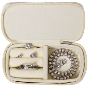 A cream jewellery wrap containing rings, earrings, and a bracelet, all featuring shiny silver accents. It has a zip closure and logo.