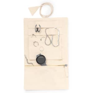 A cream jewellery wrap featuring various accessories, including earrings, bracelets, and a watch, with a zip pocket.