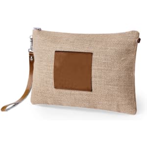 A beige toiletry bag made of burlap with a brown leather patch and a wrist strap. It features a silver zipper.