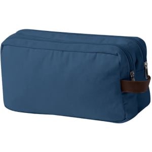 A toiletry bag in a navy blue fabric with a brown leather handle and zipped opening. Features a simple design and branding.