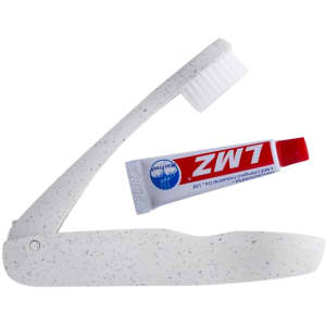A travel toothbrush with a foldable handle in white speckled design, accompanied by a small tube of toothpaste.