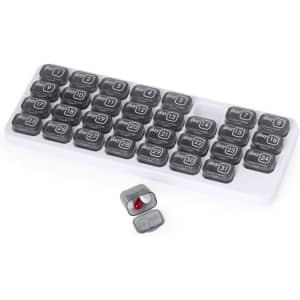 A grey and white pillbox with compartments labelled for each day of the month, featuring a small pill in one section.