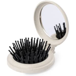 A compact hairbrush with a black bristle design and a round mirror, featuring a white casing.