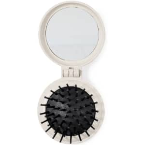 A round hairbrush with a mirror in a light colour, featuring black bristles and a compact design.