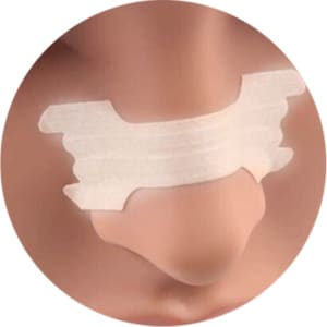 A nasal strip with a white adhesive design placed on a model's nose, featuring a smooth surface and curved edges.