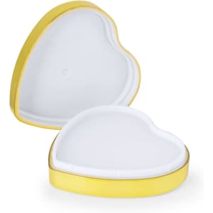 A heart-shaped lip balm container in gold, opened to reveal a white balm inside.
