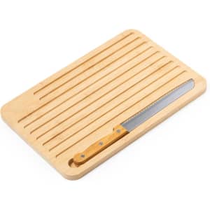 A bamboo cutting board with a slotted surface and a stainless steel knife on the side. The board features a natural wood finish.