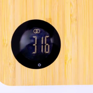 A bamboo kitchen cutting board featuring weighing scales with a digital display.