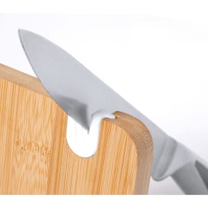 A bamboo chopping board with a stainless steel knife partially inserted, featuring a minimalist design and a logo.