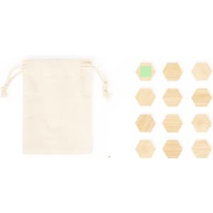 A natural fabric pouch next to a set of hexagonal wooden pieces in various shades, including one green piece.