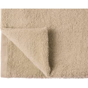 A beige hand towel with a textured surface and a folded corner, featuring a simple hem.