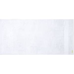 A large white bath towel with a subtle texture and a small branding label at the edge.