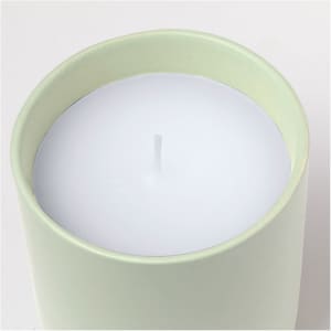A green cylindrical candle with a white wax interior and a centred wick.