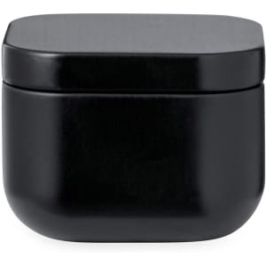 A black aromatic candle in a sleek, rounded container with a flat lid. The design is minimalistic and modern.