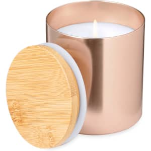 A copper cylindrical candle with a bamboo lid, featuring a lit white wick in the centre.