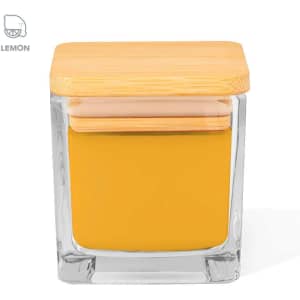 A square glass candle in yellow, topped with a bamboo lid. It features a branding logo.