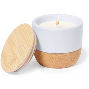 A ceramic candle with a white top, cork base, and bamboo lid, featuring a lit wick inside.
