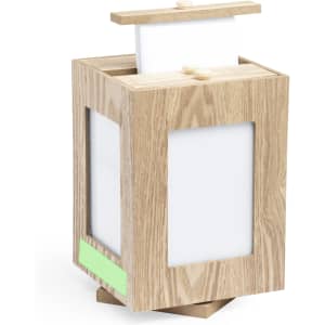 A wooden photo frame in light oak colour with transparent panels, featuring a lid and a base for stability.