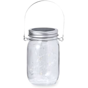 A clear glass lamp with a silver lid and handle, featuring decorative string lights inside.