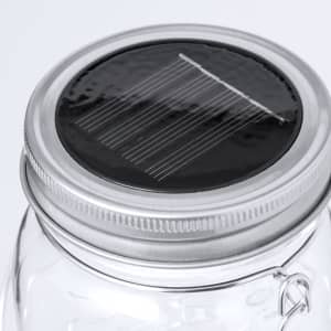 A glass lamp with a silver lid featuring a solar panel on top. The design is sleek and modern.