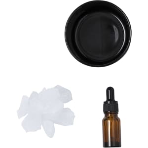 A black bowl, an amber dropper bottle, and a pile of white crystals arranged neatly.
