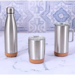 A drinkware set featuring three stainless steel insulated mugs with cork bases, displayed on a marble surface.
