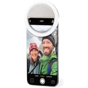 A phone featuring a circular Traxo Ring Light, with a photo of two hikers smiling in outdoor scenery.