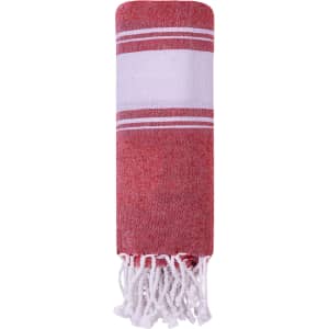 A red and white striped towel pareo with fringe edges, rolled up for easy storage. It features a logo.