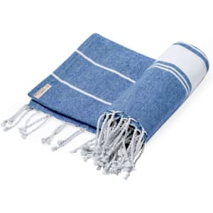 A blue and white Lainen towel pareo with tasselled edges and a small branding label.