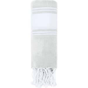 A rolled grey and white Lainen Towel Pareo with fringed edges, featuring a decorative stripe and a logo.