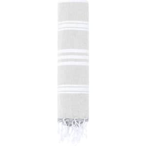 A grey and white striped towel with fringed edges, rolled up tightly for display. It features a logo.