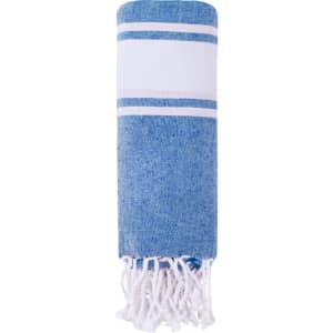 A blue and white striped pareo featuring fringe at one end. It is rolled up and showcases a soft, textured fabric.