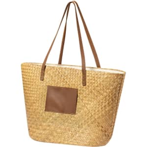 A large woven tote bag in natural straw with brown leather straps and a leather patch on the front.
