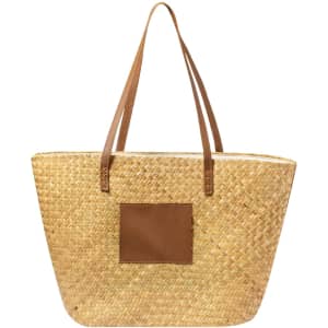 A straw tote bag with brown leather straps and a square leather patch on the front.