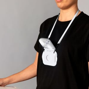 A white portable fan worn around the neck, featuring a simple design with adjustable straps.