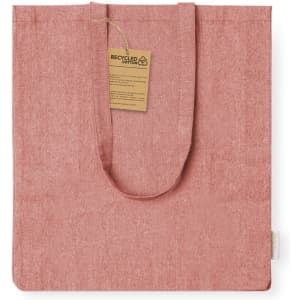 A pink tote bag made from recycled cotton with a tag attached, featuring a simple, unadorned design.