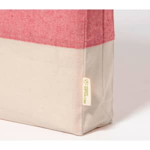 A tote bag with a pink top section and a cream bottom, featuring a small tag with a logo.