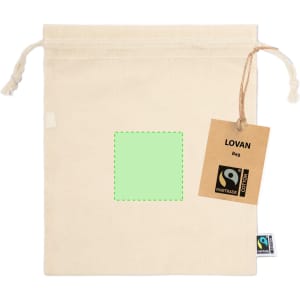A natural cotton drawstring bag with a tag and a blank green square for customisation. Features a Fairtrade logo.