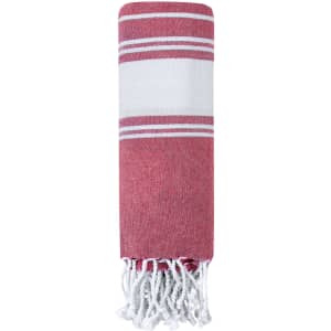 A folded red and white striped towel with fringe edges. The towel is made from a lightweight, textured fabric.
