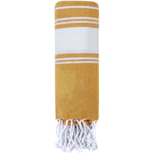 A yellow and white striped towel pareo with tassels on one end, featuring a simple design and branding.