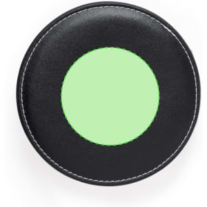 A circular black coaster with a green stitched inner circle, featuring a smooth surface and a simple design.